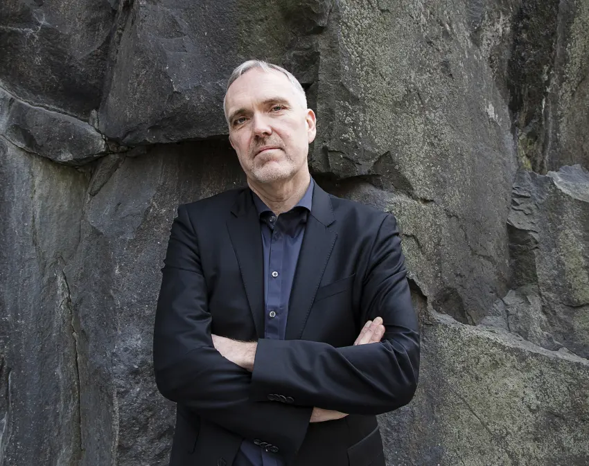 Jon Karlung, vd för Bahnhof, står med armarna i kors framför en mörk klippvägg.
