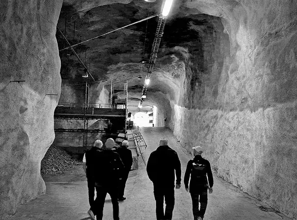 Ingång till Bahnhofs underjordiska datacenter Bahnhof Bunker i Göteborg, med grottväggar, industriell belysning och besökare som går in i tunneln.