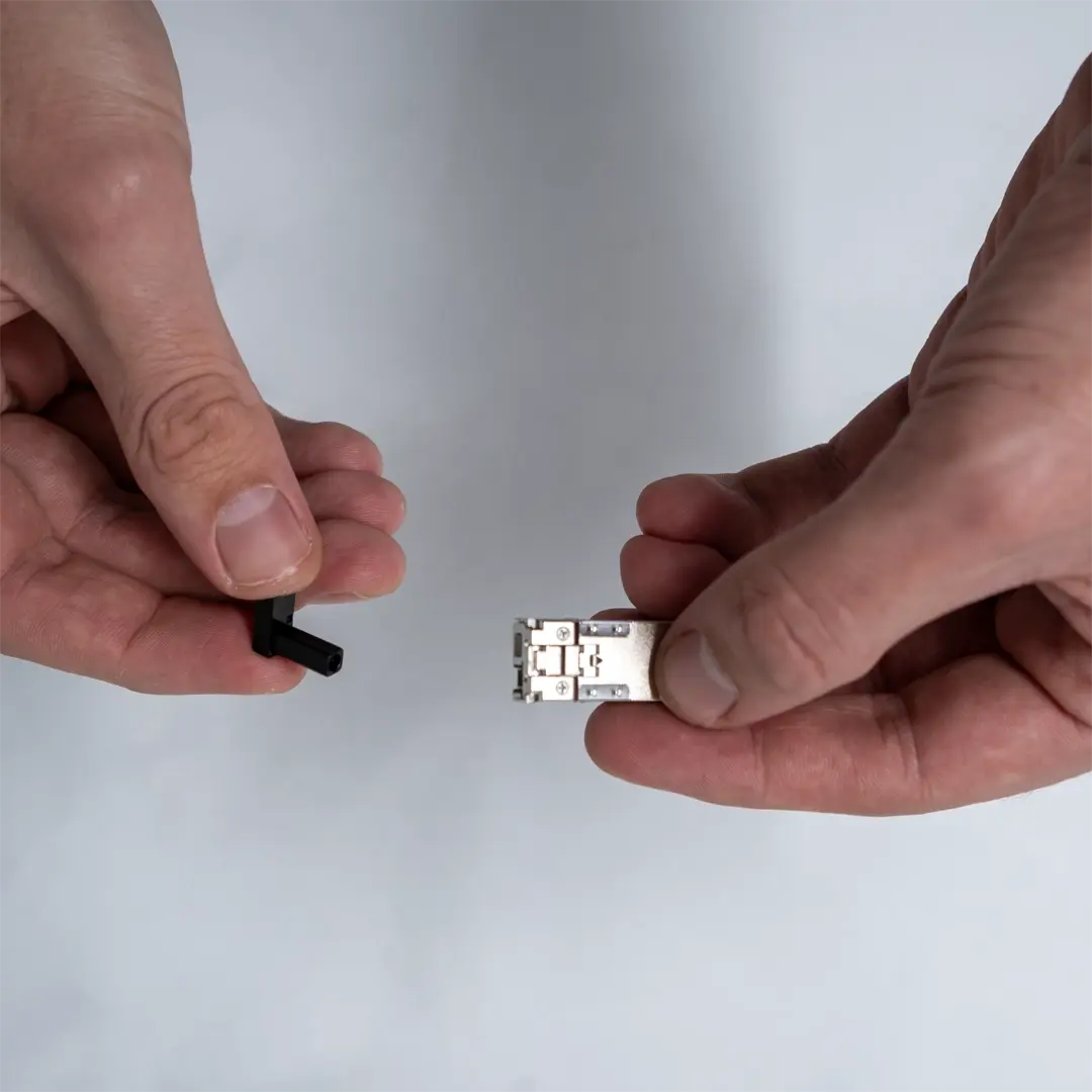 En person håller en SFP-modul i ena handen och tar bort en svart skyddskåpa med den andra.