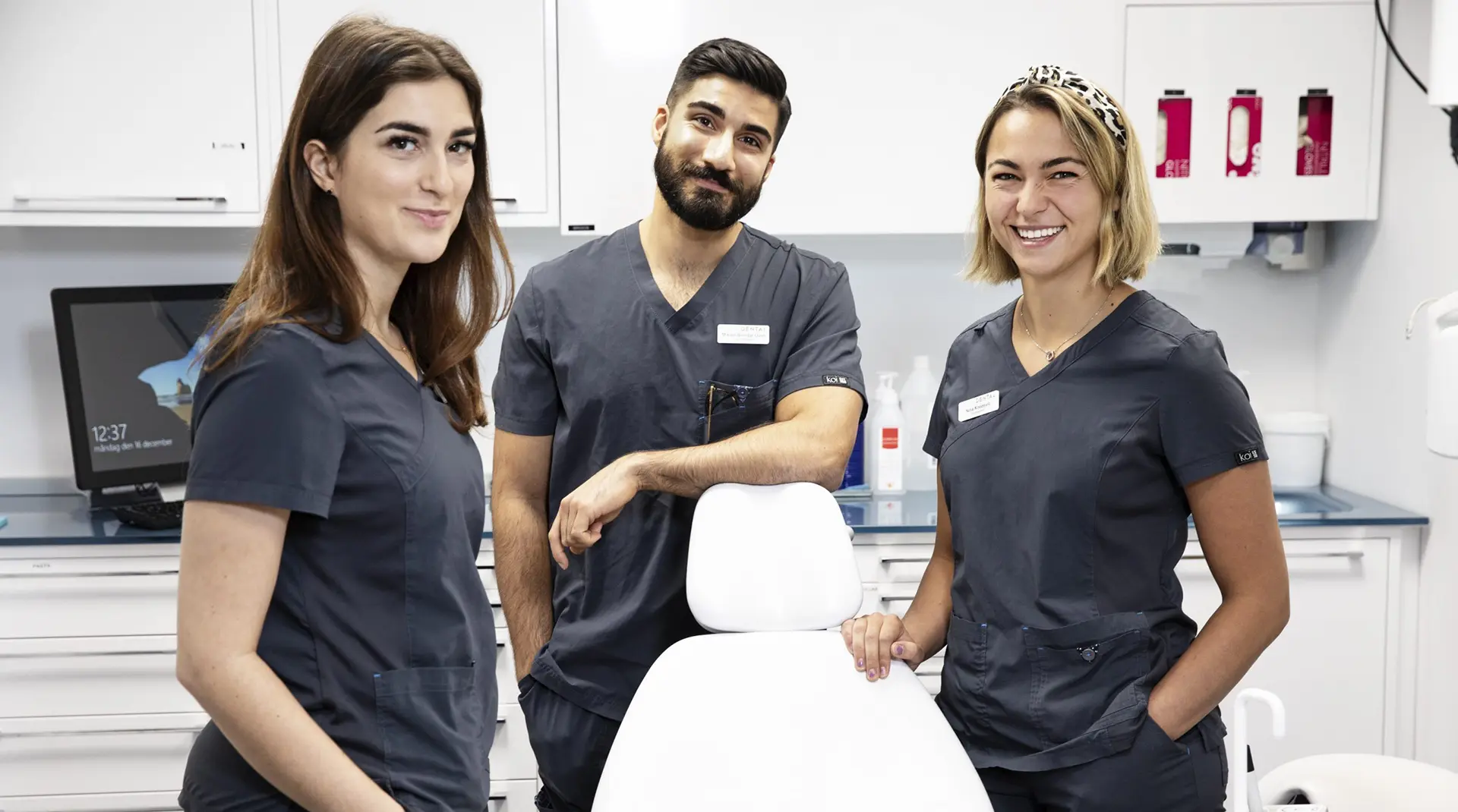 Tandvårdsteam på Aqua Dental står i en modern klinikmiljö med behandlingsstol och utrustning.