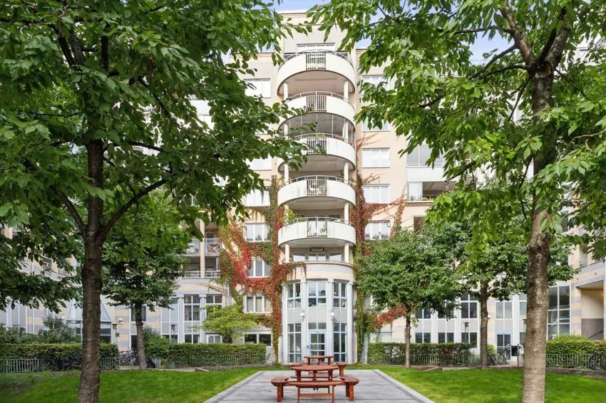 Innergård med bostadshus i BRF Fatbursviken 2 på Södermalm i Stockholm, omgiven av grönska och balkonger.