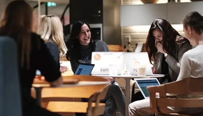 Medarbetare arbetar tillsammans med laptops i Funnels kontorsmiljö med trådlöst nätverk.