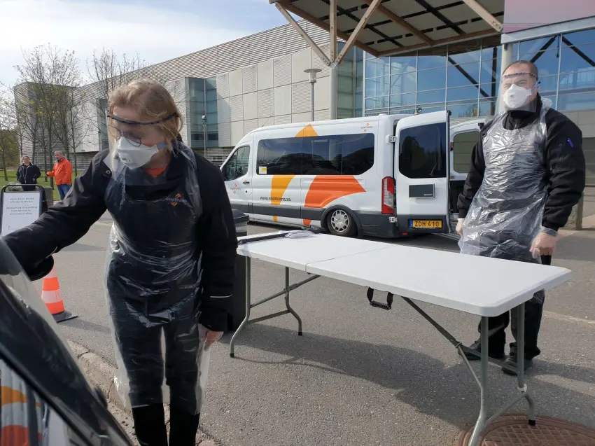 Personal från InfoSolutions i skyddsutrustning genomför covid-19-provtagning utomhus vid teststation.