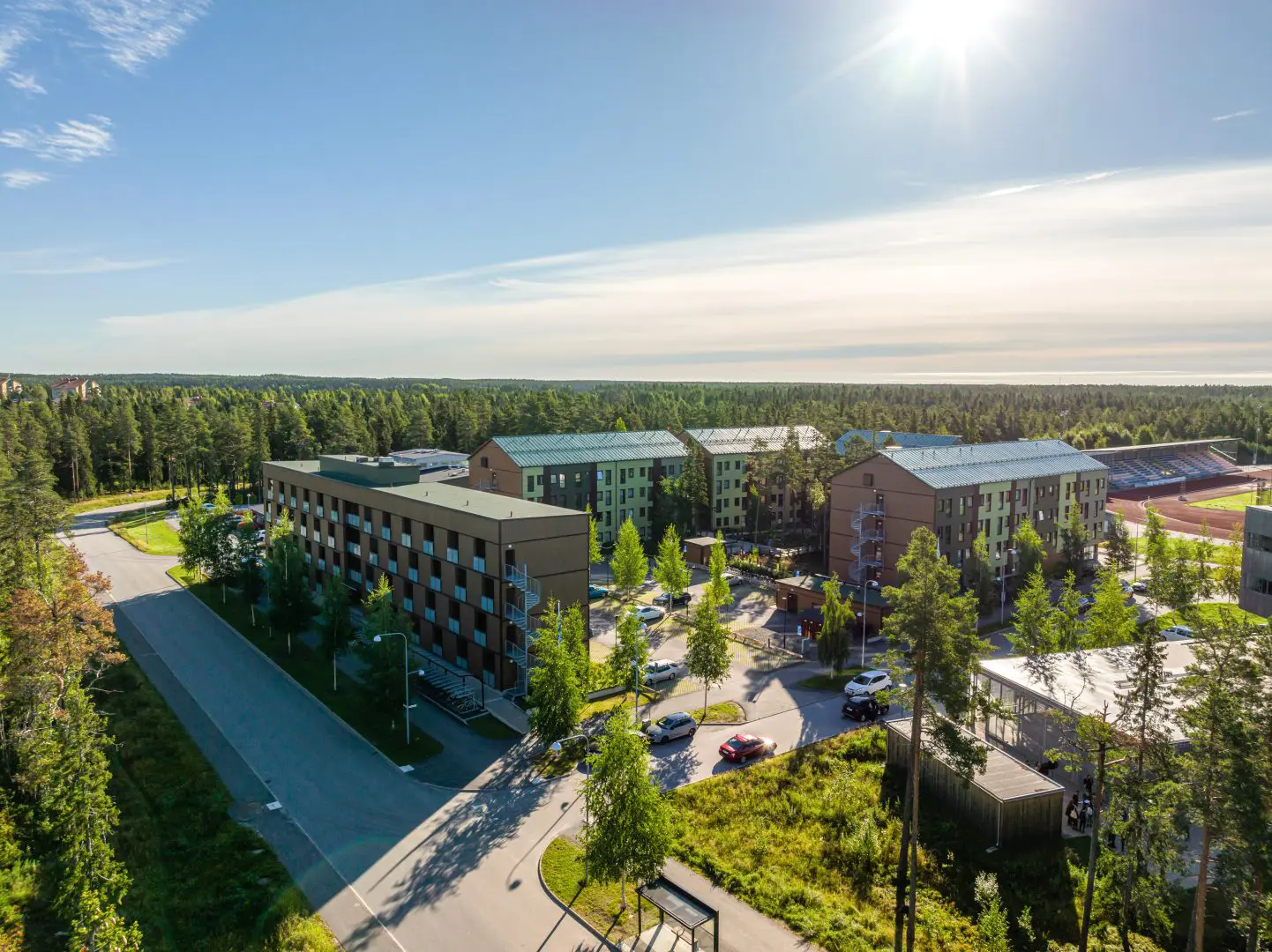 Flygfoto över K2A:s hållbara hyresbostäder i trä, omgivna av grönska, där Bahnhof levererar blixtsnabbt fiberbredband.