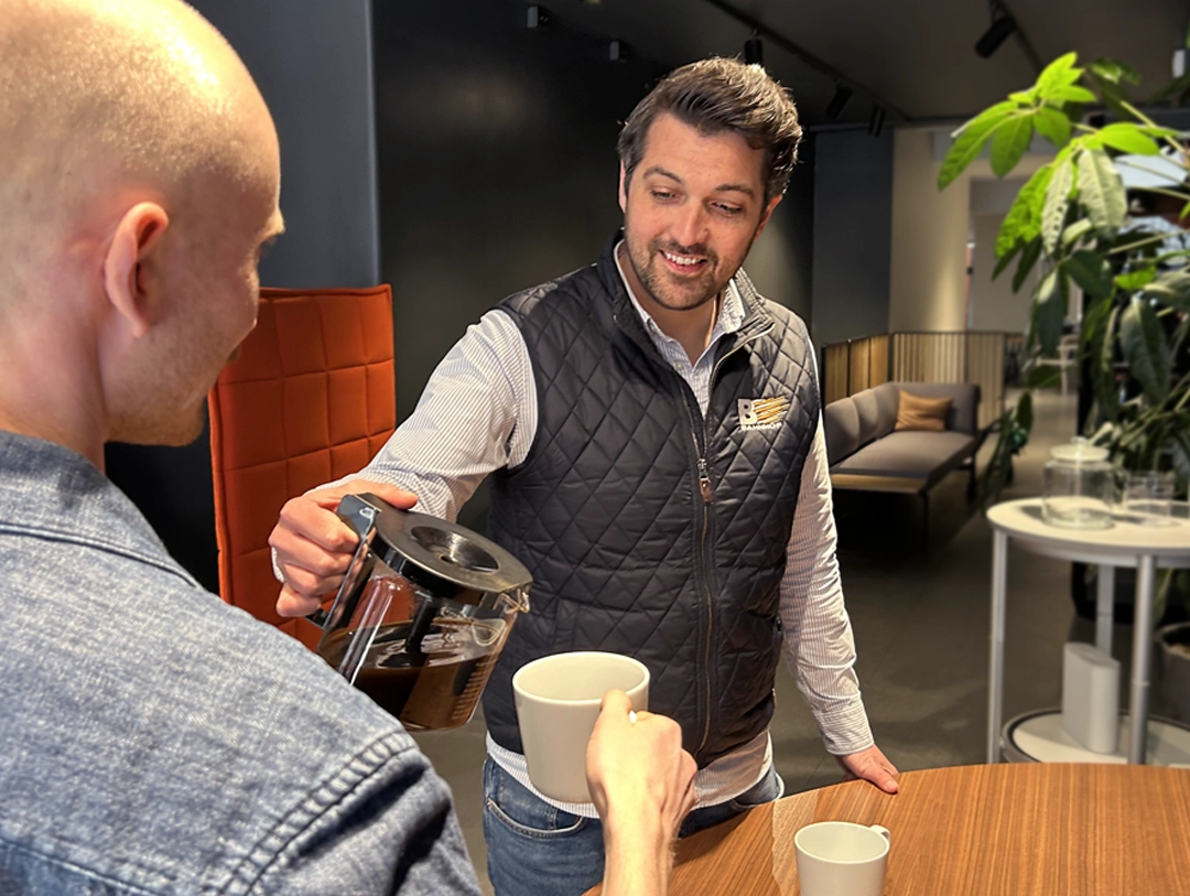 Bahnhof-personal med kaffekopp hälsar på en hund utanför butiken i Stockholm.