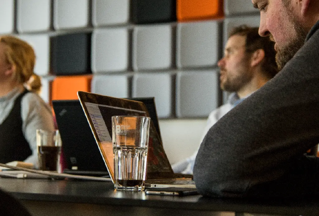 Personer arbetar tillsammans med datorer vid ett mötesbord.